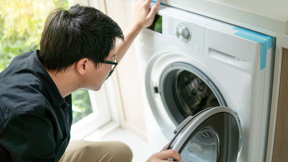 Man looking into the drum of a dryer.