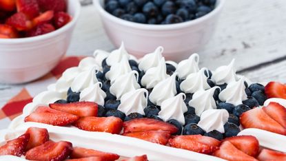 Patriotic American flag cake. Bowls of blueberries and strawberries in the background