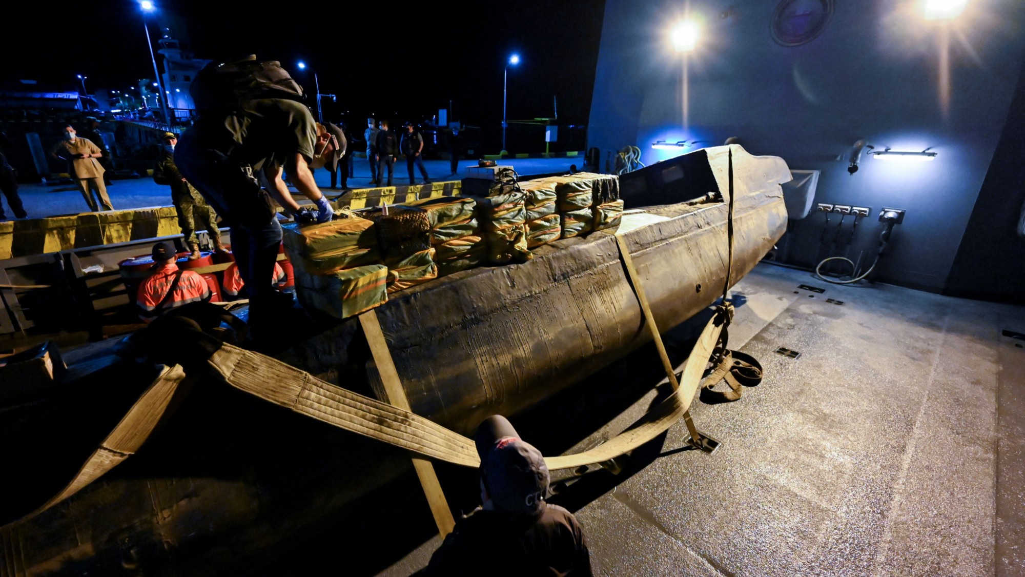 Law enforcement inspecting packages with cocaine on a narco submarine seized in Buenaventura, Colombia on March 20, 2021