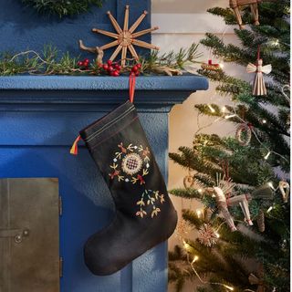 A black VINTERFINT Christmas stocking on a blue fireplace