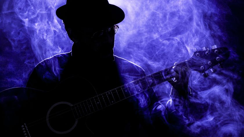 Silhouette of an unrecognizable male musician playing guitar in a nightclub