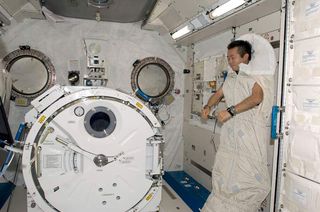 Japanese astronaut Koichi Wakata is photographed in a sleeping bag attached to the racks in the Kibo laboratory of the International Space Station.