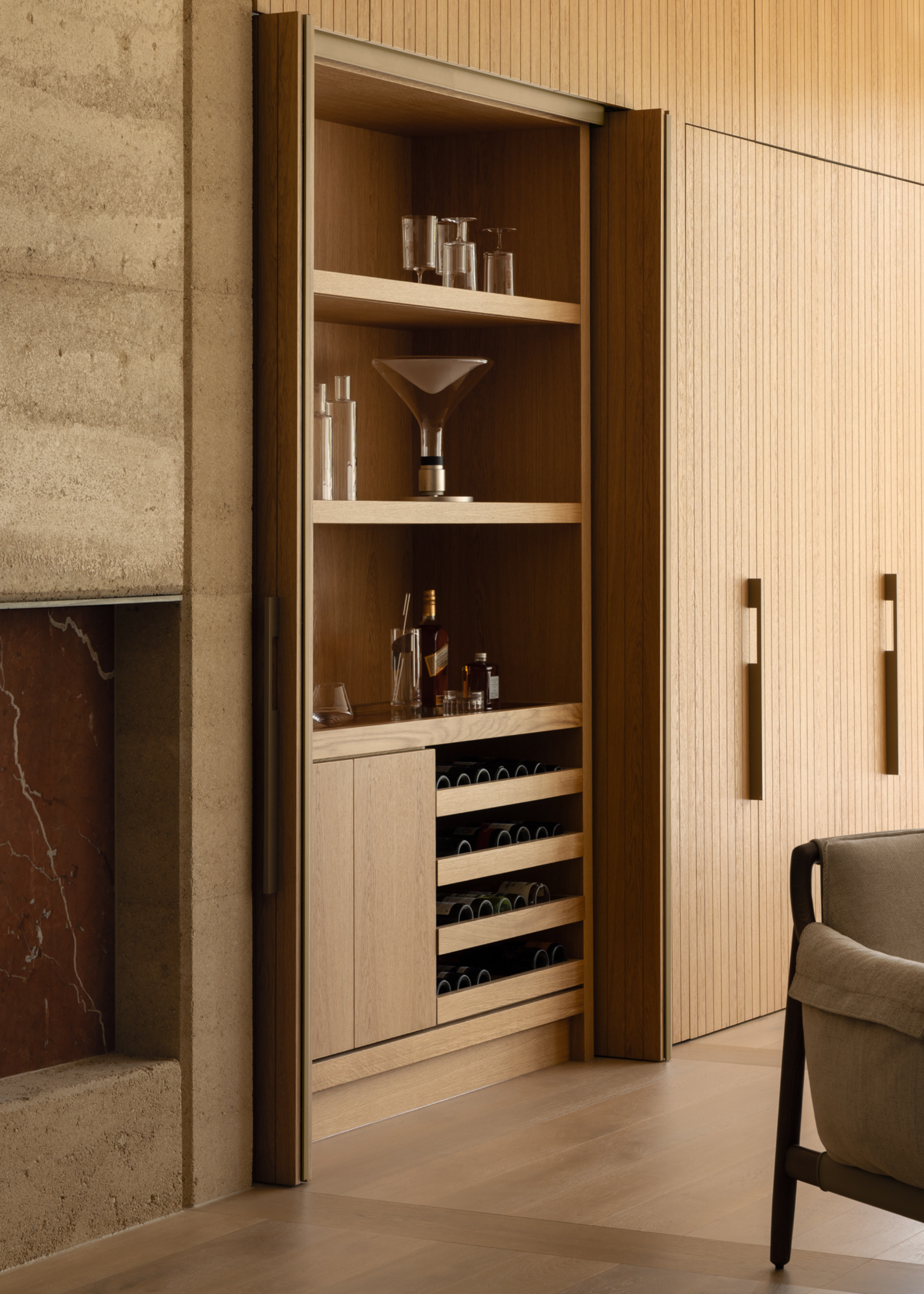 An open dining concept with a bar corner featuring shelves of cocktail glasses and wine bottle drawers