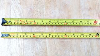 Top down view of two tape measures on wooden table top