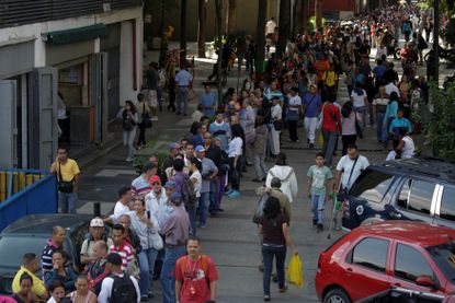 People wait in line to deposit money in Caracas, Venezuela.