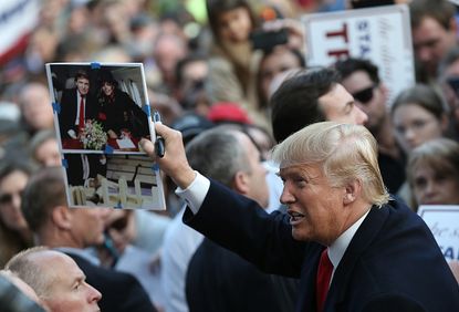 Donald Trump holds up a photo of himself with Michael Jackson.