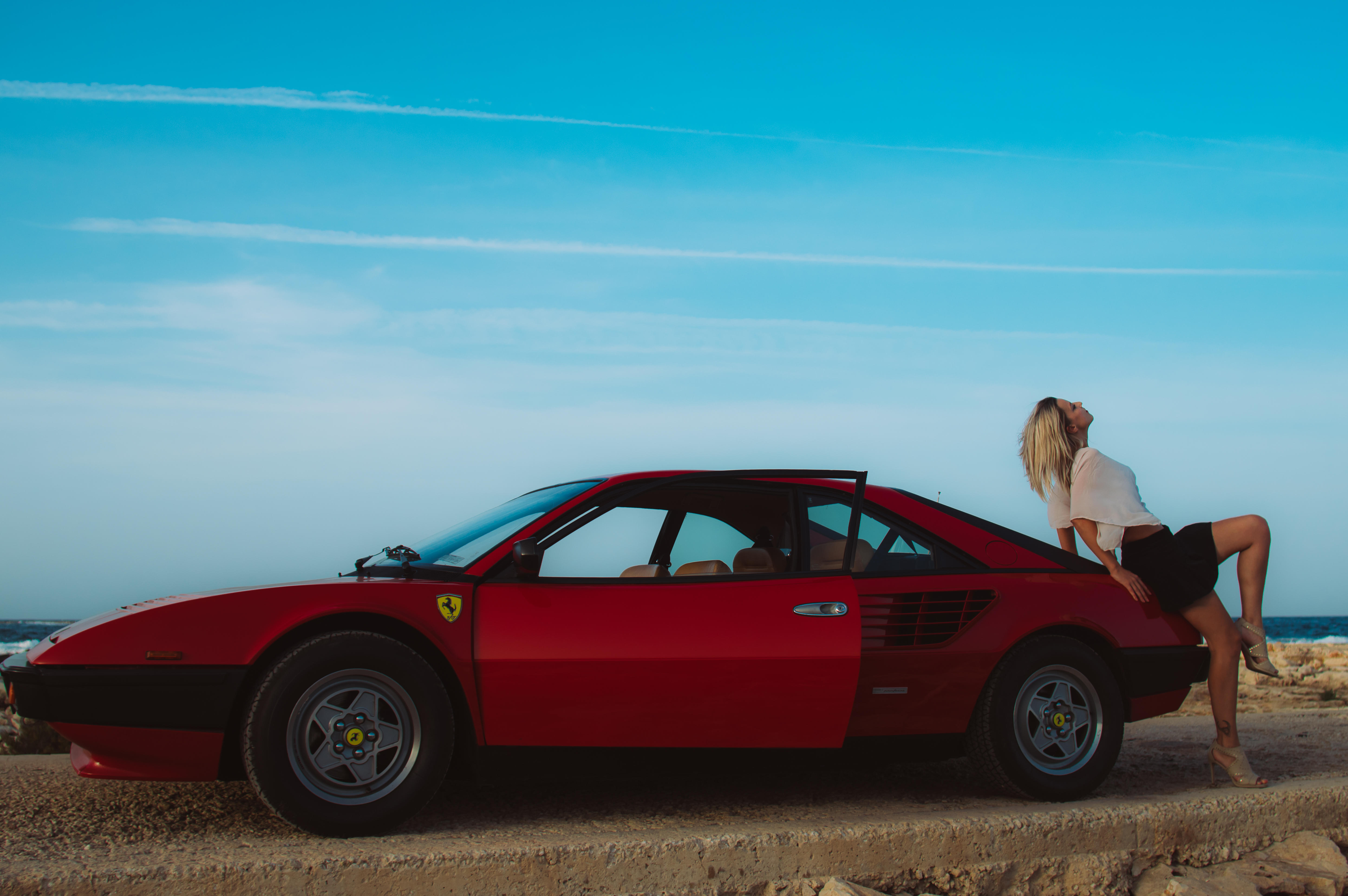 A woman leans on a red ferrarir