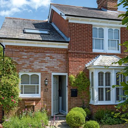 bricked house exterior with white windows and garden