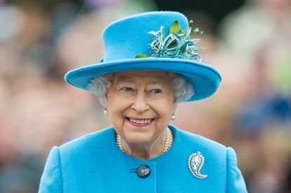 queen elizabeth in a blue jacket and hat