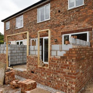 building a house with brick wall glass window and wooden frame