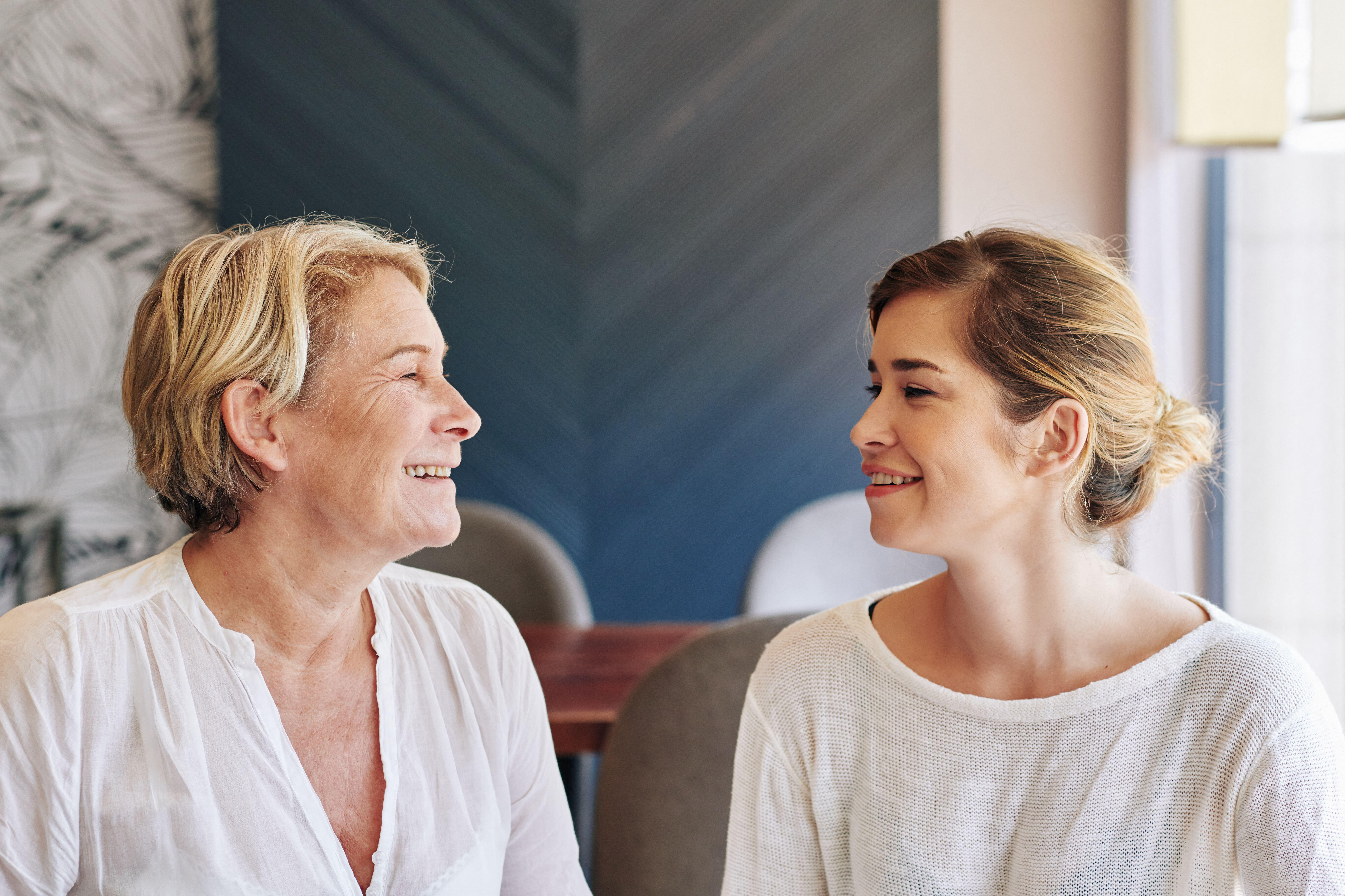 2B18BWY Cheerful mature woman and her adult daughter discussing stories when meeting in cafe on weekend