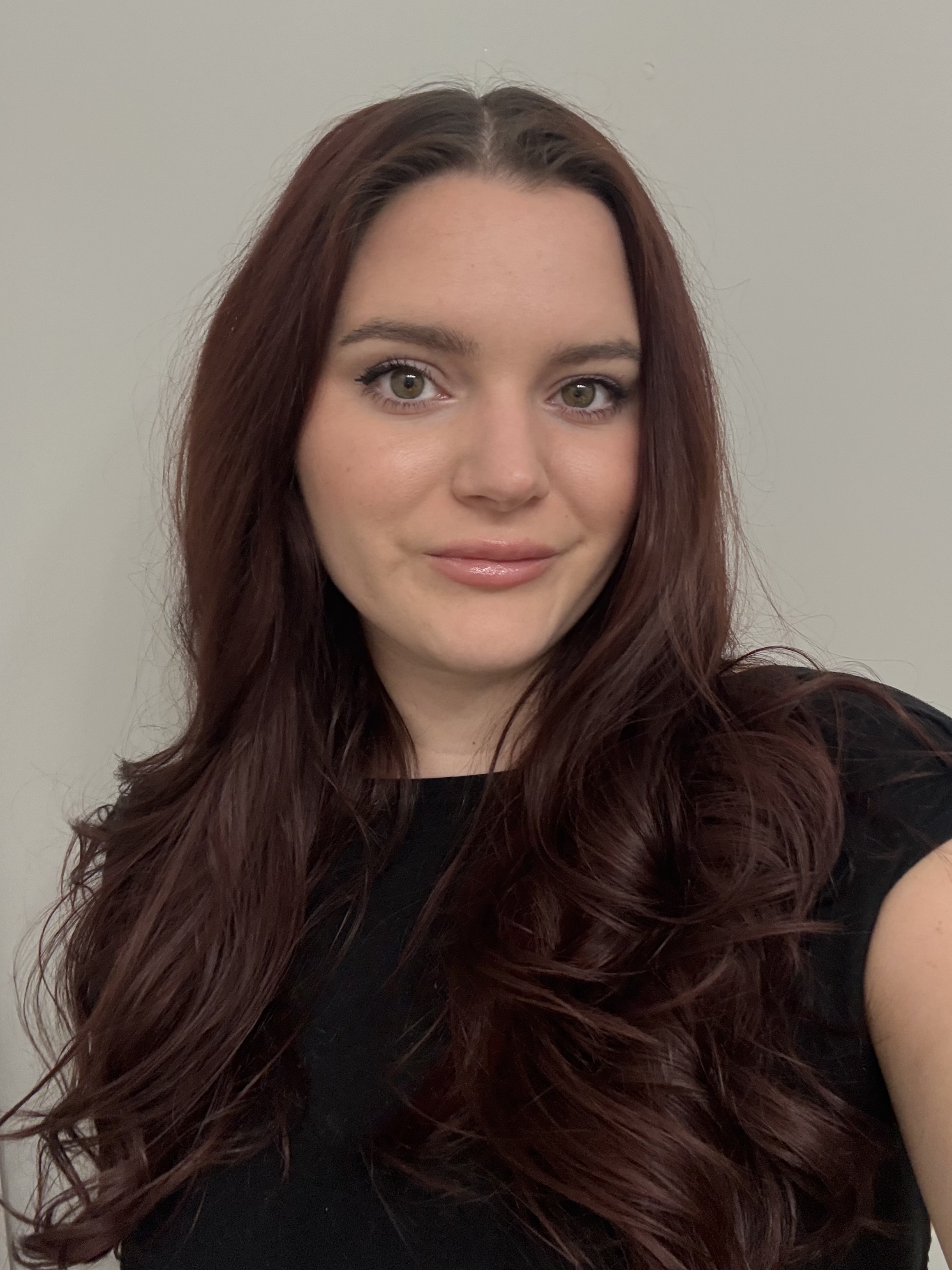 A woman wearing a black top with reddish brown hair, smiling at the camera