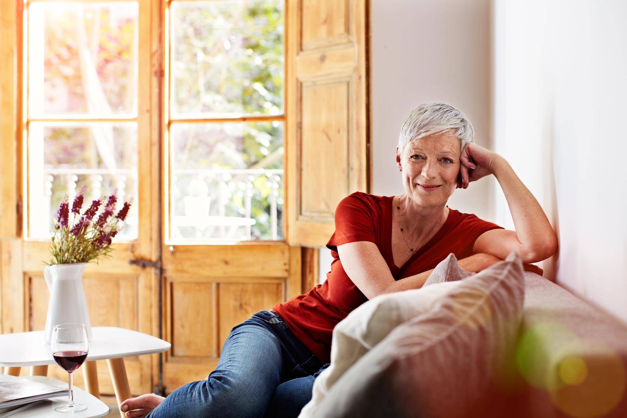Portrait of a smiling woman relaxing on her sofa at home with a glass of wine