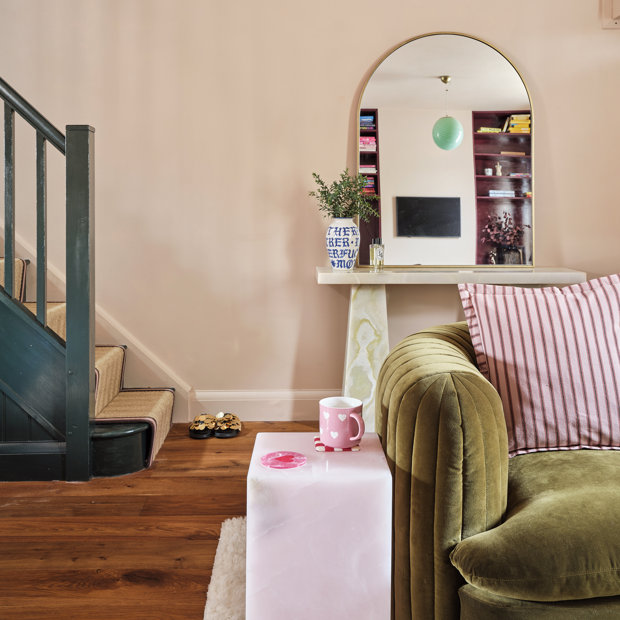 a small open plan living room with console table and large mirror beside a stairwell