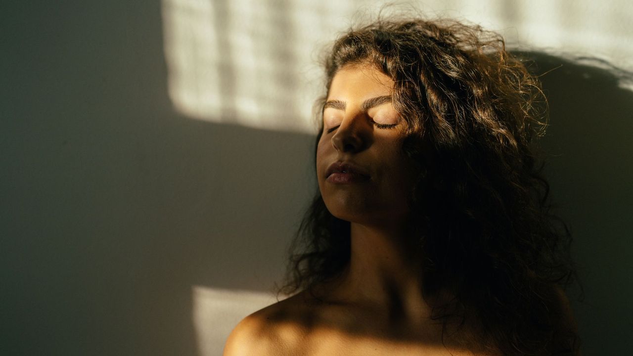 Woman enjoying sunlight through the window - skin inflammation