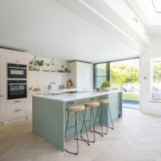 large bright kitchen with pale green kitchen island and cream cabinets 