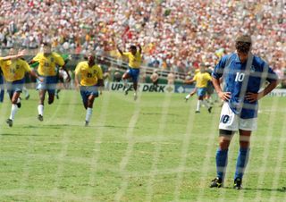 Italy's Roberto Baggio bows his head after missing a penalty in the shootout of the 1994 World Cup final as Brazil's players celebrate victory.