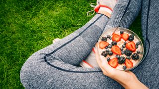 Woman in sportswear eating porridge with berries