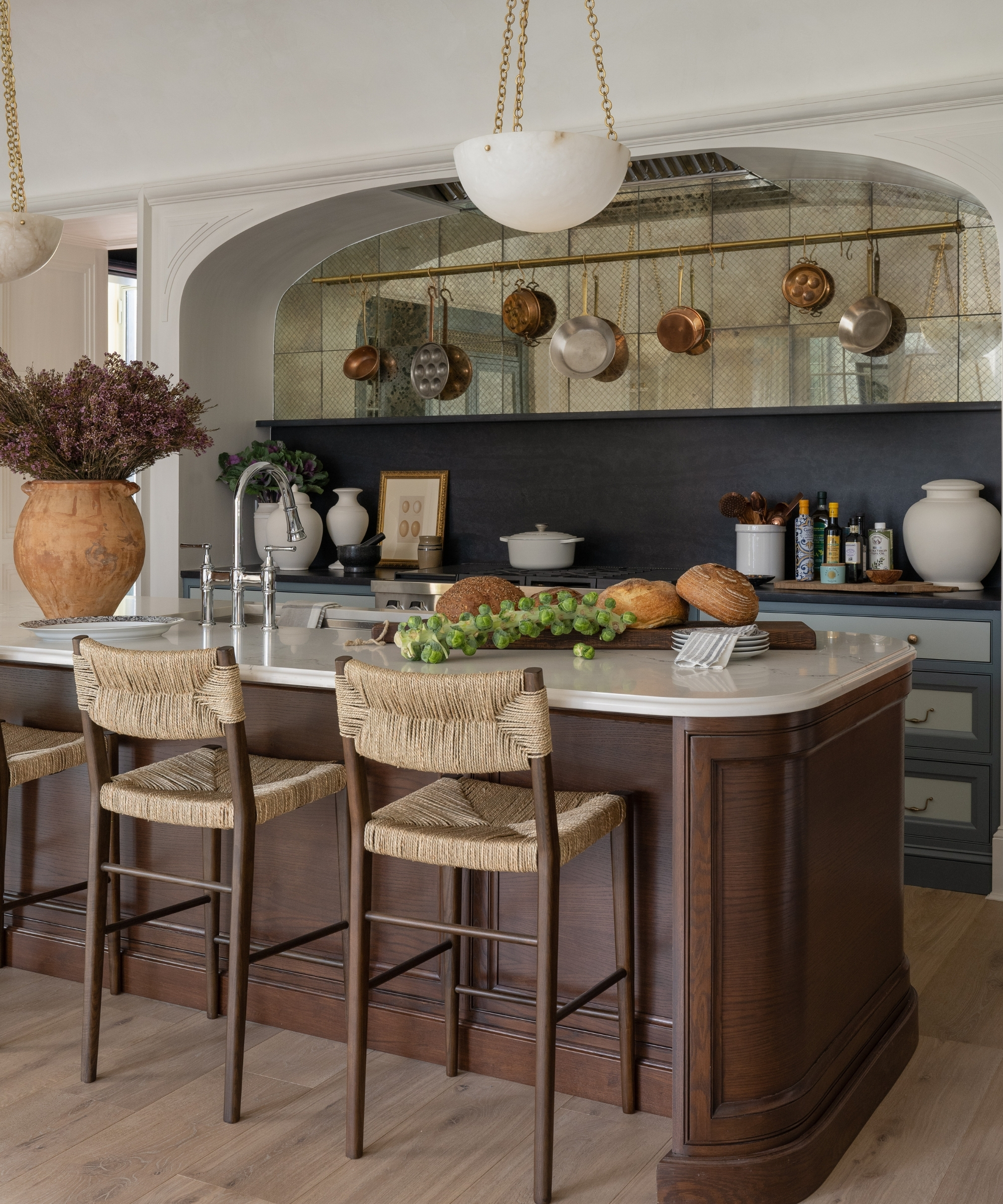 A small kitchen with white walls, dark wood cabinets and island, and an antiqued mirrored backsplash