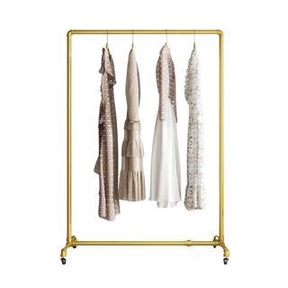 A gold clothes rail on wheels with four dresses hanging on hangers