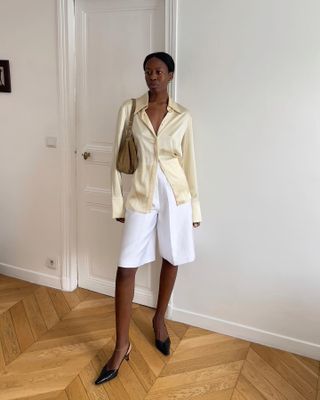 French woman wearing a silky blouse and white shorts