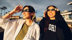 two women looking at the sun wearing solar eclipse glasses