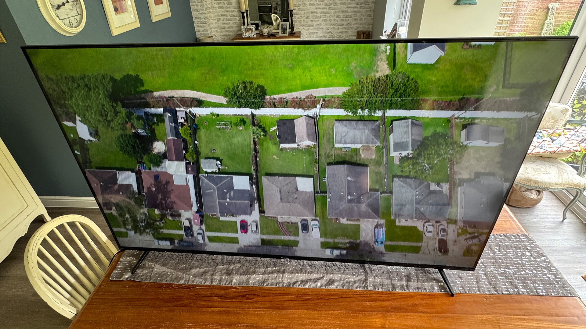 Sharp GK4245K 70-inch 4K TV on dining table, on screen is aerial view of houses