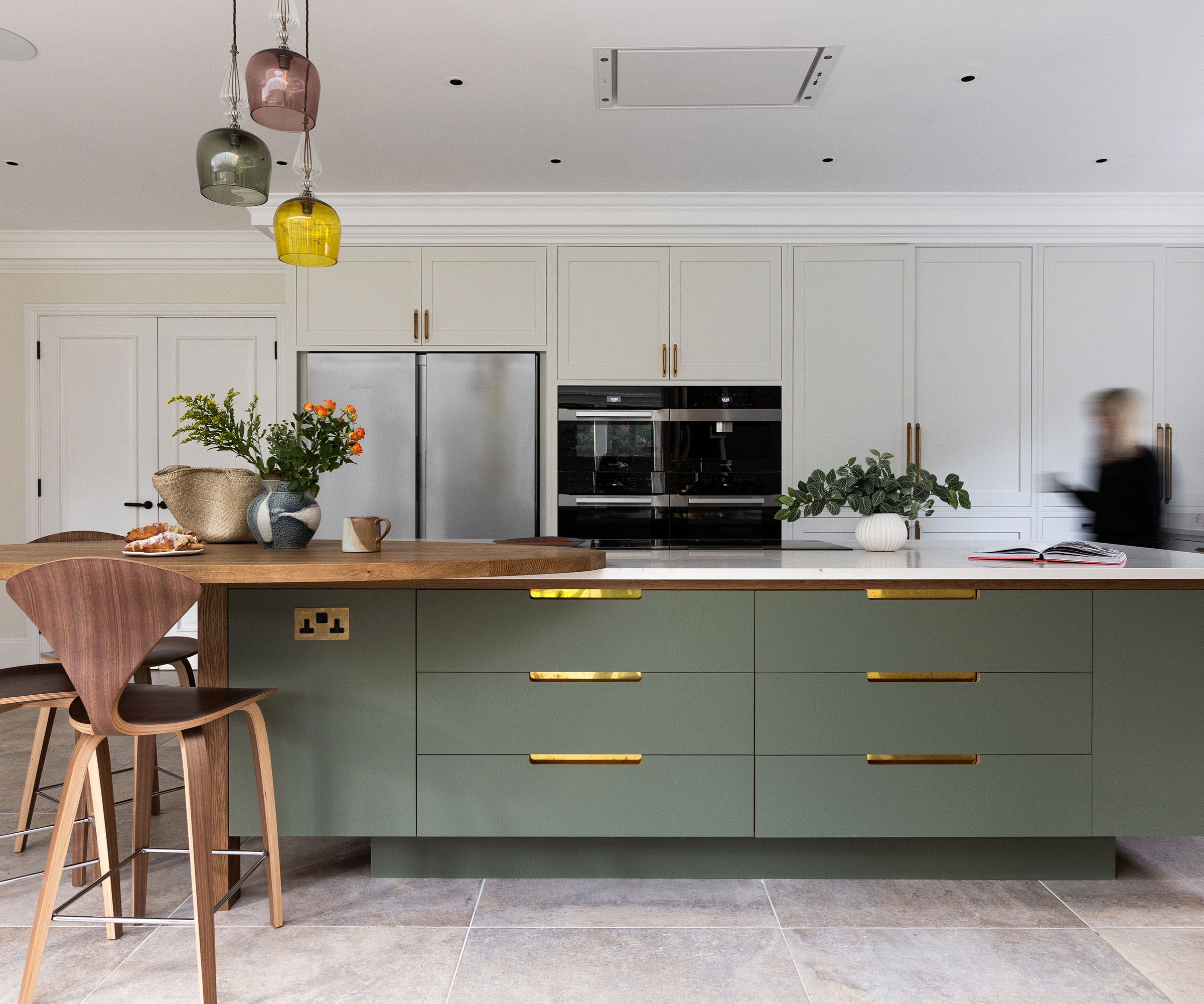 large kitchen with large green kitchen island with circular breakfast bar and large format floor tiles