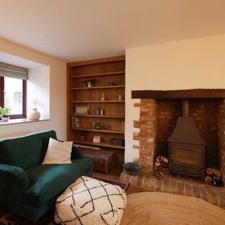 living room with green armchair and pouffe in front of woodturning fireplace