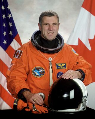 Portrait of Canadian astronaut Dave Williams in an orange spacesuit.