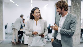 Shot of two coworkers having a discussion in modern office. 