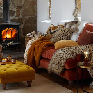 cosy living room with orange sofa and faux fur throws and cushions