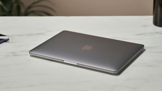 MacBook Pro 13" M2 på en bordplade i et kontormiljø.
