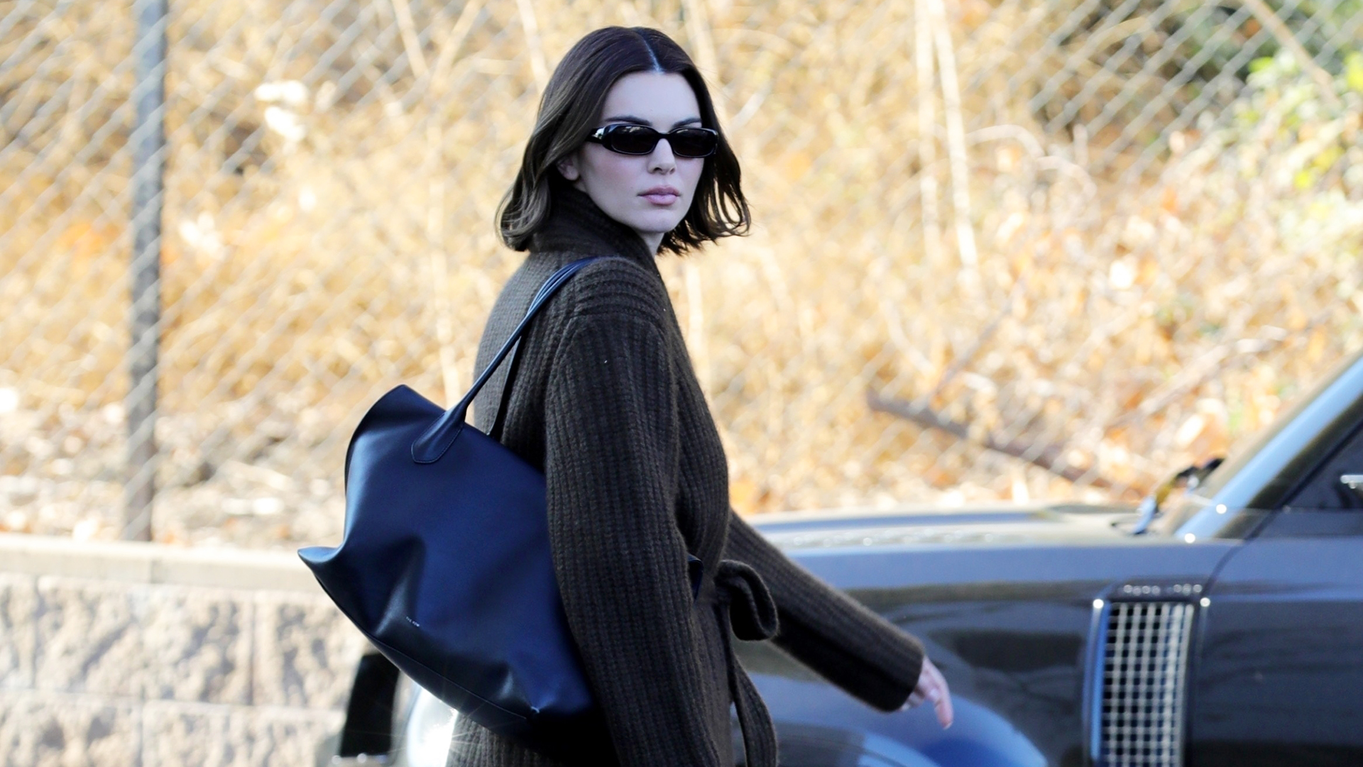 Kendall Jenner wearing a sweater and black The Row tote bag with black leggings and Ugg boots.