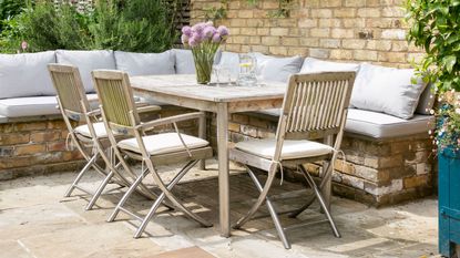 stone patio with wooden outdoor dining furniture