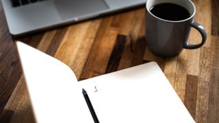 notebook with a list on it and a pen and coffee mug