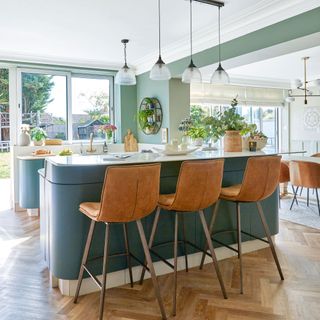 Green kitchen peninsula with leather bar stools