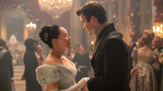 Sophie and Benedict facing each other at a ball and holding hands.