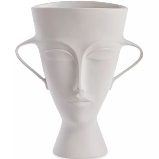 A white ceramic vase with a face carved out