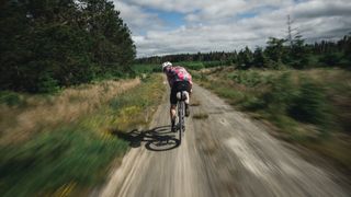 A cyclist riding quickly along a gravel track
