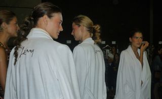 Backstage, three models wear white robes with "Lenny" embroidered on the back
