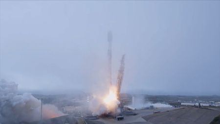 A white rocket lifts off into the fog blanketing its launch pad.