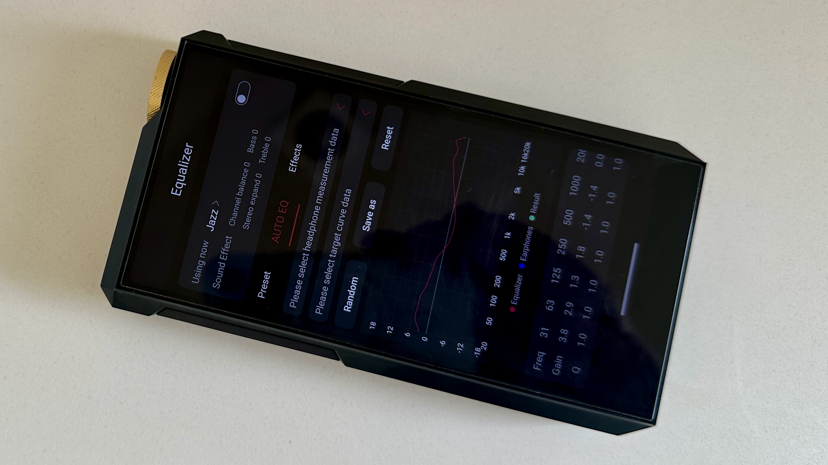 The FiiO M27 player with screen and dial showing, and content on the screen, on beige or yellow background