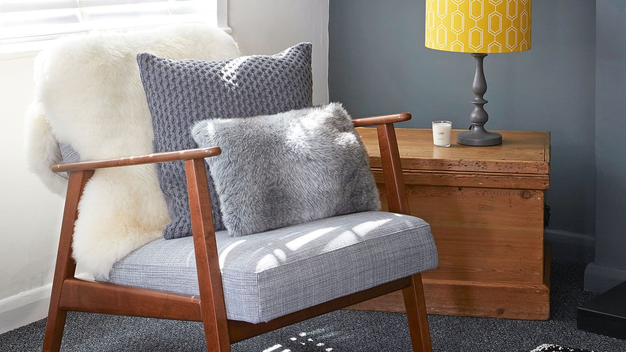 Corner of grey and white living room with chair and open shelving