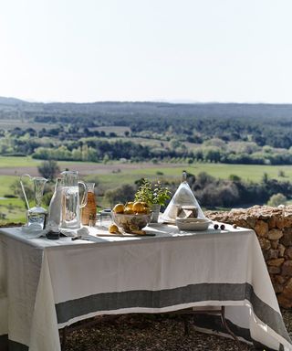 A table covered in a table cloth and breakfast items with a scenic view beyond