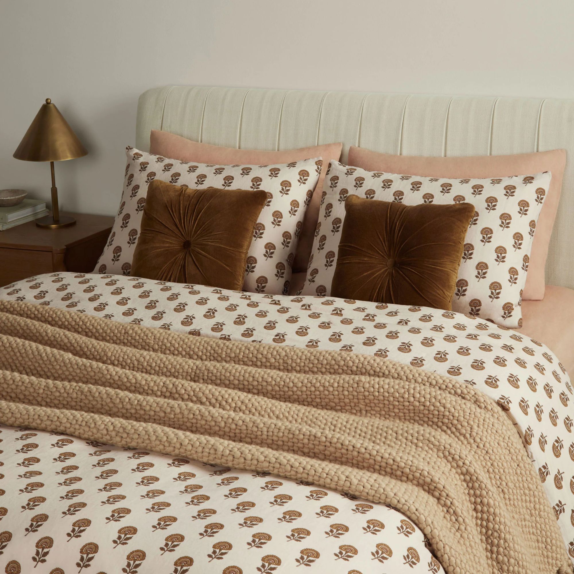 Fall bedding in a white and floral print paired with brown velvet throw pillows and a cream throw