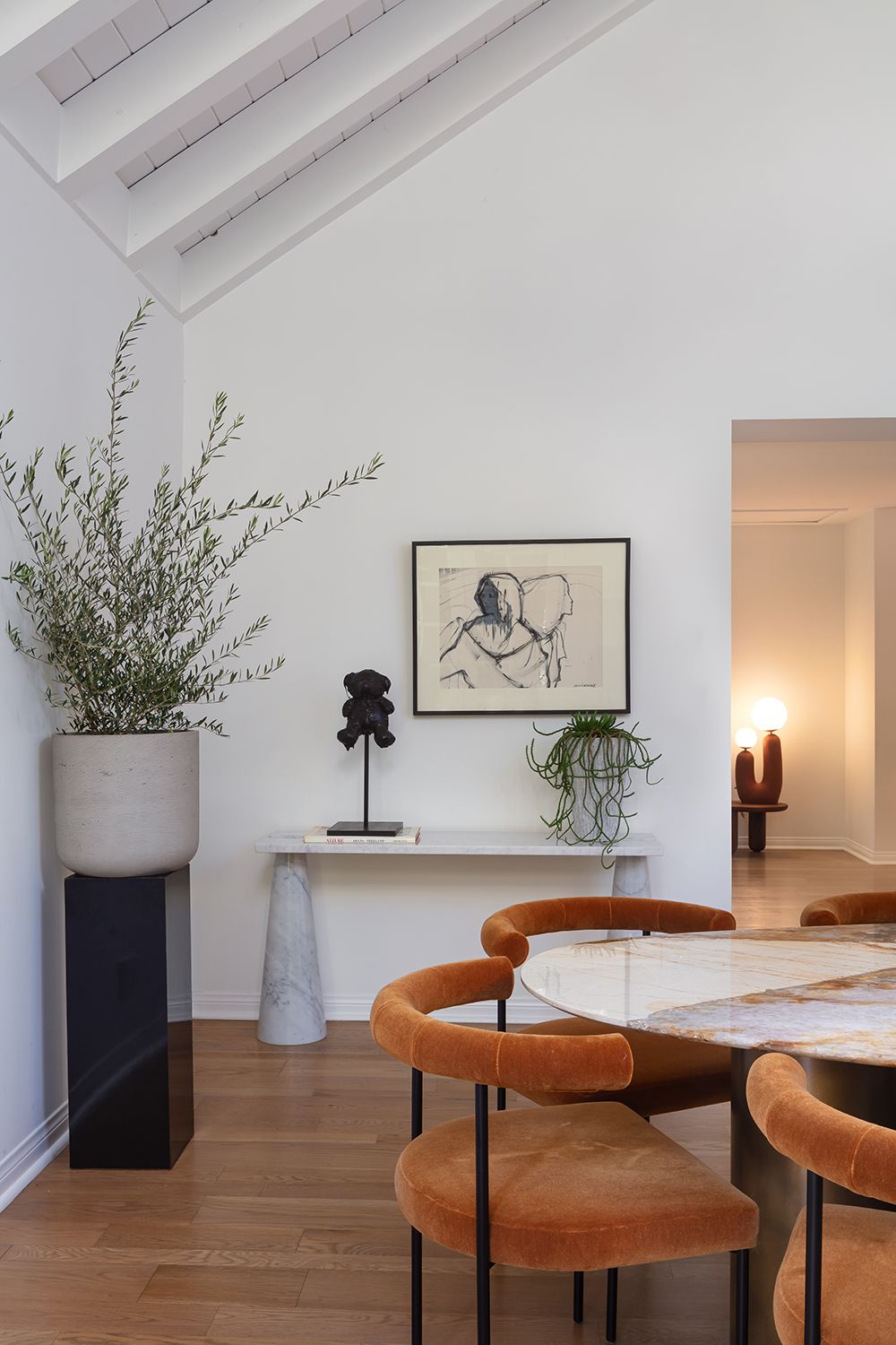 dining room with oval marble table, terracotta dining chairs and marble side table with house plants