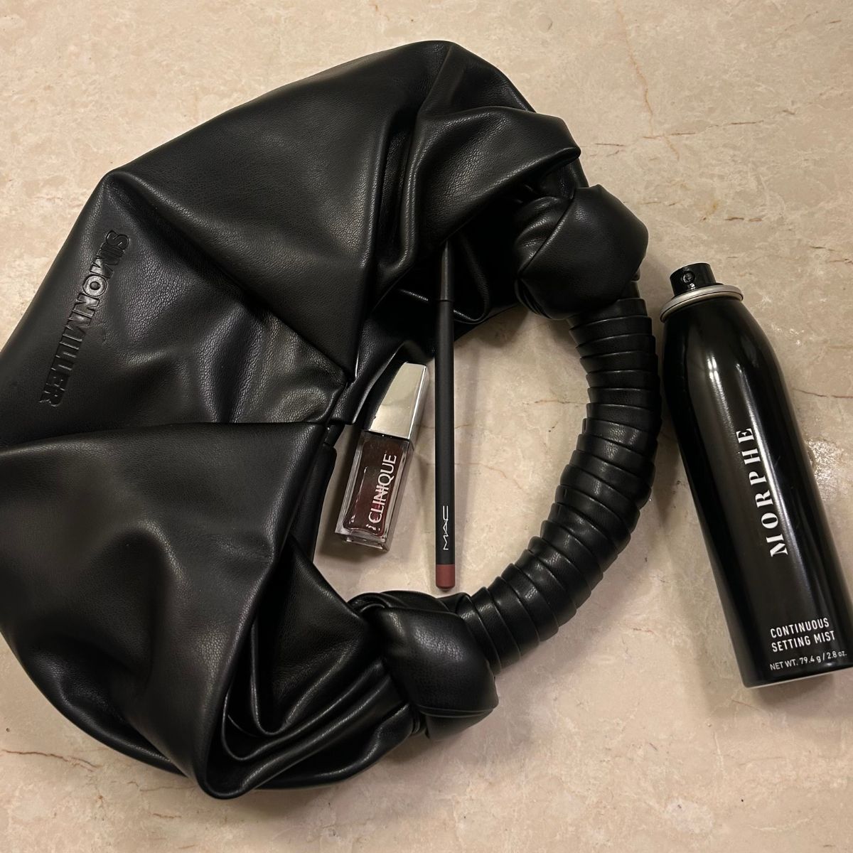 Image of Who What Wear associate beauty editor Alyssa Brascia's purse with Ulta beauty products spilling out of it.