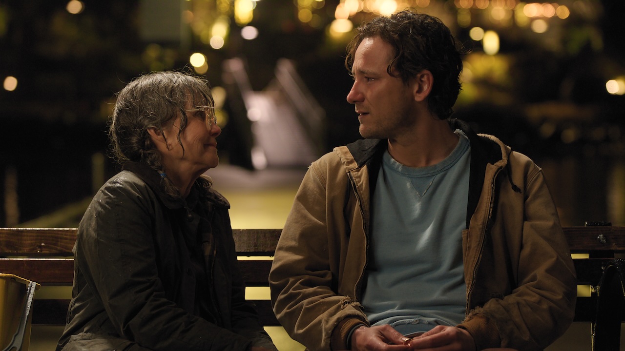 Sally Field and Lewis Pullman facing each other on a bench at night in Remarkably Bright Creatures