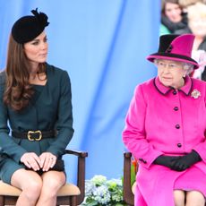 Kate Middleton wears a dark green dress with a black hat and Queen Elizabeth wears a bright pink coat